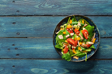 Spinach salad with cherry tomatoes in a bowl on a wooden background
