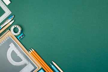 Pupil's desk with stationary on green background. Preparation to school.