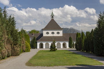 Fototapeta premium Church in the city Fussen in Germany with a green meadow in front and trees on both sides