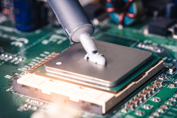 the close up image of technician squeezing the fresh thermal paste compound on the top of cpu in...