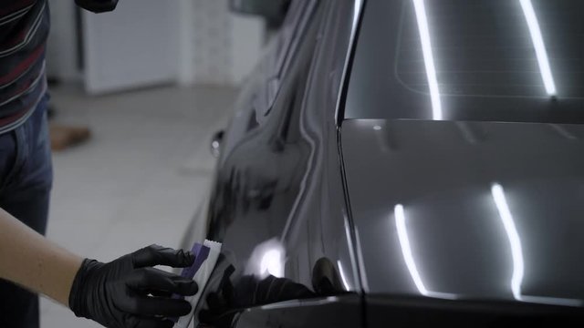 Close up shot of a man in gloves ceramic coating clean black car.