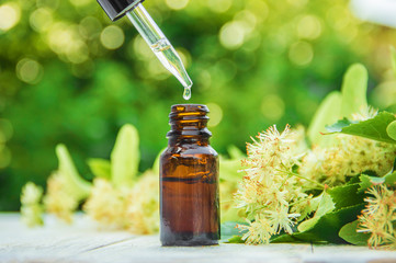 linden extract and flowers in a small bottle. Selective focus. - obrazy, fototapety, plakaty
