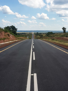 Long straight asphalt road with diminishing perspective in countryside of Angola, Africa