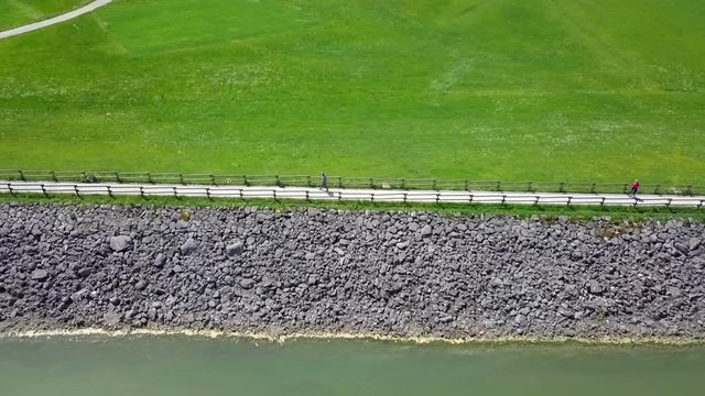 Aerial: Flying over green lake beside dam on it on sumer sunny day. Flying with drone and filming on beautiful sunny summer day.