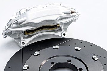 Performance braking system, 
New silver racing caliper and new perforated disk. 
Auto parts on white background.