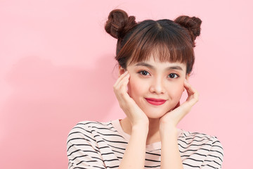 Beauty makeup. Fashion teen girl model in t-shirt. Asian girl with matte lips and bun hairstyle posing over studio pink background..