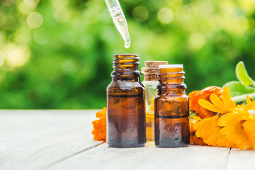 calendula extract and flowers in a small bottle. Selective focus.  - obrazy, fototapety, plakaty