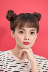 Portrait of attractive young asian woman in t-shirt top on red background. Funny girl with bun dark hairstyle