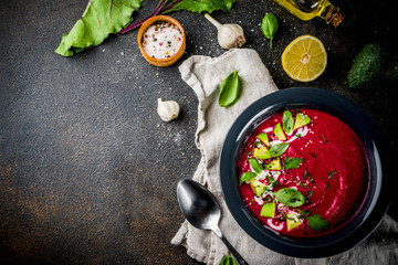 Vegan food, summer cold Beetroot gazpacho soup with lemon, avocado and fresh herbs copy space top view