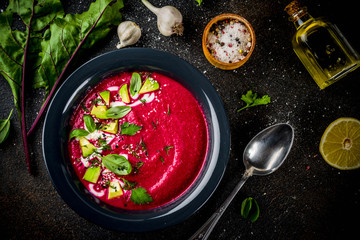 Vegan food, summer cold Beetroot gazpacho soup with lemon, avocado and fresh herbs copy space top view