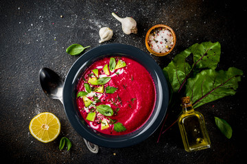 Vegan food, summer cold Beetroot gazpacho soup with lemon, avocado and fresh herbs copy space top view
