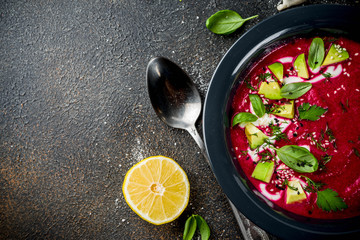 Vegan food, summer cold Beetroot gazpacho soup with lemon, avocado and fresh herbs copy space top view