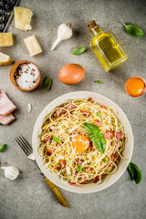 Traditional italian pasta, spaghetti carbonara with bacon, creamy sauce, parmesan cheese, egg yolk and fresh basil leaves grey stone background copy space