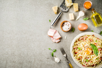 Fototapeta na wymiar Traditional italian pasta, spaghetti carbonara with bacon, creamy sauce, parmesan cheese, egg yolk and fresh basil leaves grey stone background copy space