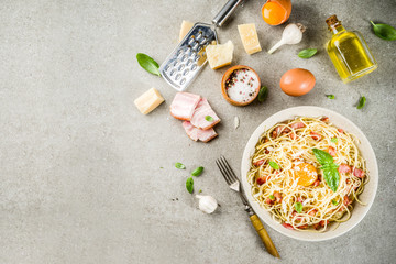 Traditional italian pasta, spaghetti carbonara with bacon, creamy sauce, parmesan cheese, egg yolk and fresh basil leaves grey stone background copy space