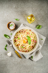 Traditional italian pasta, spaghetti carbonara with bacon, creamy sauce, parmesan cheese, egg yolk and fresh basil leaves grey stone background copy space