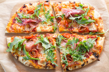 Wood fired pizza with tomato sauce, mozzarella, marinated cherry tomatoes, topped with rocket and parma ham. 