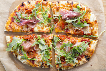 Wood fired pizza with tomato sauce, mozzarella, marinated cherry tomatoes, topped with rocket and parma ham. 