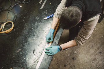 Man in workshop marking wood with a pen