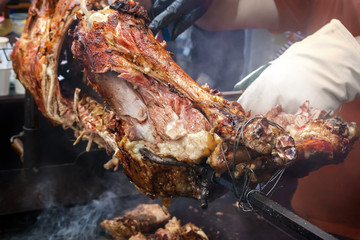 Cook cuts the finished lamb into pieces on a spit over hot coals. Outdoor grill