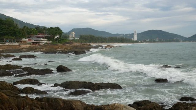 sea wave hit the rock shore seascape , Patong sand beach Phuket  parasail , tree and mountain are  background ,