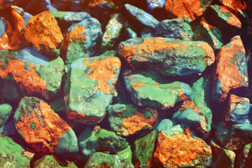 closeup stone drenched in orange, blue and green paint