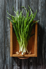 top view of bunch of ripe leeks in box on wooden tabletop