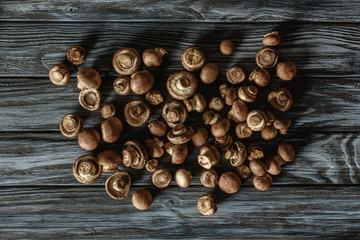 top view of pile of raw brown champignon mushrooms on wooden surface