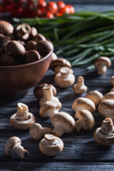 close-up shot of delicious raw champignon mushrooms with leek on dark wooden table