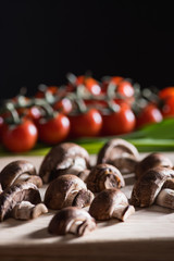 close-up shot of halved champignon mushrooms on wooden cutting board on black