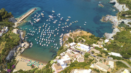 Aerial view of the beach and the small harbor of Cala Feola on the island of Ponza, in Italy. There are many boats and motorboats of tourists anchored in the bay and sheltered in the mountains.