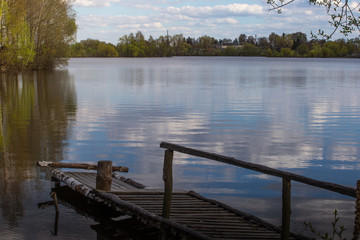 Over flooded with reed in river in spring. Wood bridge. Europe