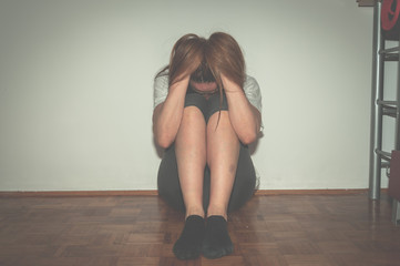 Depressed and lonely girl abused as young sitting alone in her room on the floor feeling miserable...