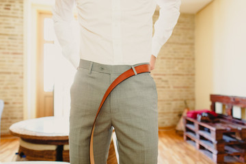 Man fastening his belt to his pants