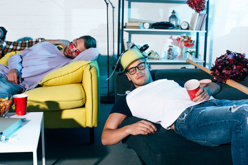 drunk young men sleeping on couches after home party
