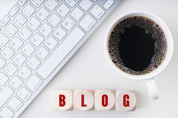 Würfel mit dem Wort BLOG am Arbeitsplatz mit Tastatur und Kaffee