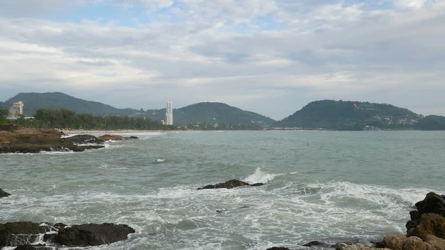 sea wave hit the rock shore seascape , Patong sand beach Phuket  parasail , tree and mountain are  background ,