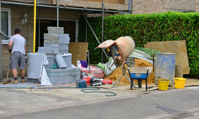 A building site in the UK with a labourer sweeping up some rubble.