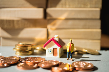 Miniature people, engineer standing with stack coins and mini house using as business, industry and financial concept