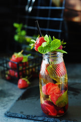 Strawberry lemonade drink, refreshing summer lemonade with fresh berries and mint on dark background