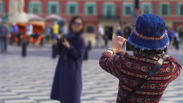 Female tourist taking photo of her friend in European city centre, travel
