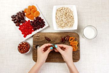 the girl is preparing her breakfast. The girl clears her date fruit in oatmeal porridge on a cutting board. Useful and healthy breakfast. light background