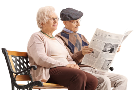 Seniors sitting on a bench and reading a newspaper