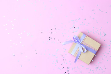 gift and sparkles of confetti on a colored background top view. minimalism, insta. flatlay 