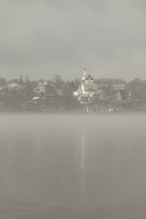 Fototapeta premium Church on the banks of the River in the fog