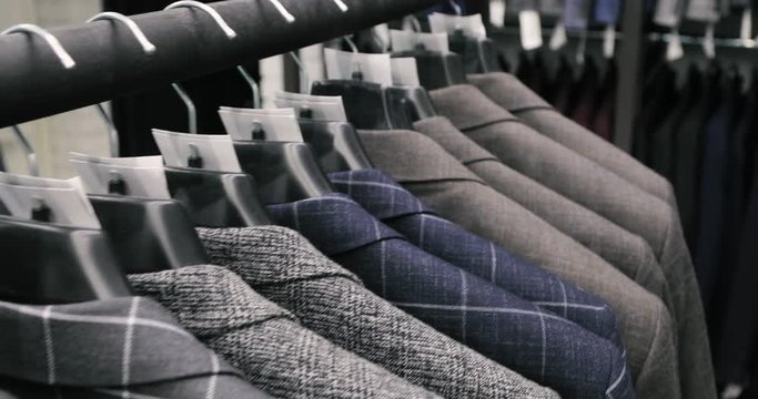 Men's suit at tailor's shop. Men's hands choose a jacket in their wardrobe. Male choosing