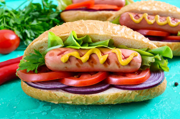 Tasty hot dogs on a bright background. Grilled sausage with tomatoes, red onions, lettuce, mustard in a crispy loaf. Street food. Fast food.