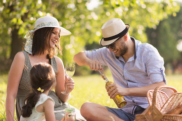 a young three-member family spends time on a sunny meadow