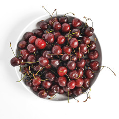 Obraz na płótnie Canvas Fresh cherry in droplets of water on a white plate, isolated on white background, top view.