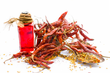 Close up of dried red chilies with its extracted oil in a transparent bottle isolated on white with...